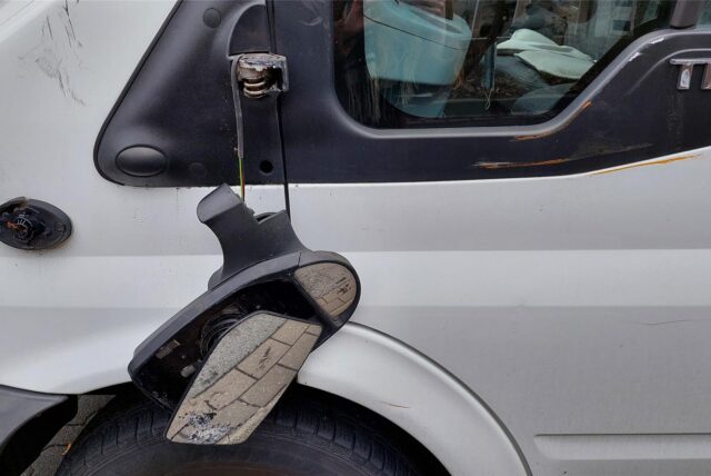 Ein Seitenspiegel eines Autos hängt nur noch befestigt an einem Kabel an der Halterung herunter