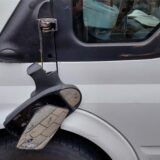 Ein Seitenspiegel eines Autos hängt nur noch befestigt an einem Kabel an der Halterung herunter