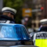 Zwei Polizeibeamte stehen zwischen zwei Einsatzfahrzeugen der Polizei.