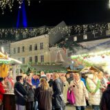 Der Weihnachtsmarkt 2024 in Unna. Viele Menschen haben sich auf dem Alten Markt versammelt und genießen die Weihnachtszeit. Im Hintergrund ist der blau beleuchtete Kirchturm zu sehen.