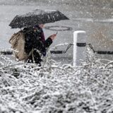 Eine Person geht mit einem Regenschirm während es schneit.