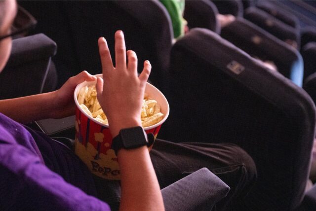 Ein Kind isst Popcorn in einem Kinosaal.