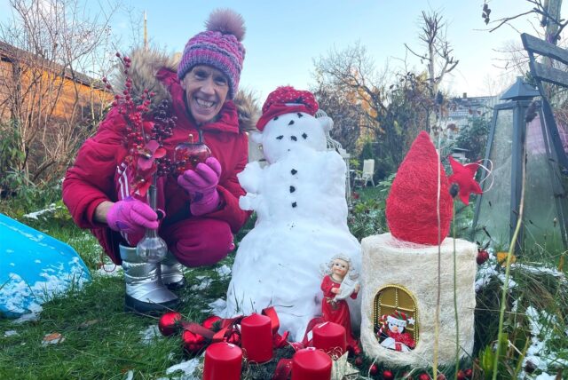 Wetterexperte Burkhard Dreischer hockt in seinem Garten in Dortmund neben einem Schneemann.