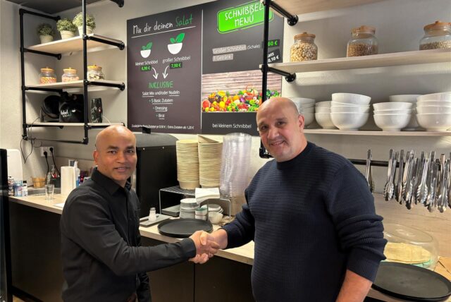 Der neue Inhaber Hossain Howlader (r.) mit dem ehemaligen Besitzer Mustafa Nergiz von Schnibbelgrün in Unna. Hinter der Verkaufstheke geben sich die beiden Männer die Hand.