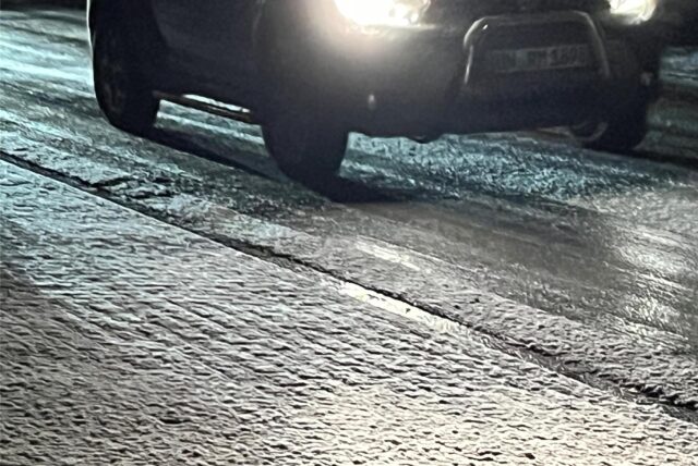 Schnee auf glatten Straßen, Auto mit Scheinwerferlicht in der Dunkelheit.