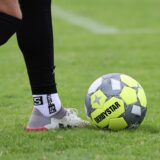 Ein Derbystar-Fußball liegt auf dem Rasen. Ein Fußballer spielt ihn mit dem Fuß.
