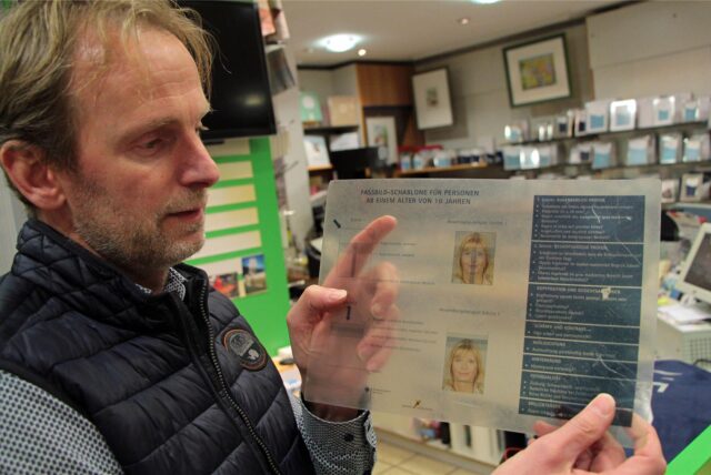 Ein Fotograf zeigt eine Schablone für das Anfertigen von Passbildern