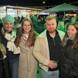 Eine Gruppe von Menschen lächelt in die Kamera während sie Glühwein trinken.