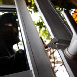 Auf dem Bild sieht man einen Einbrecher, der ein Fenster aufmacht.