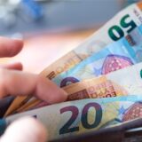 Eine Frau hält ein Portemonnaie mit Geldscheinen in der Hand.