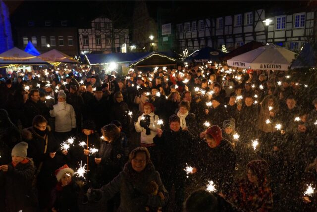 Eine Menschenmenge mit brennenden Wunderkerzen auf dem Weihnachtsmarkt in Werne