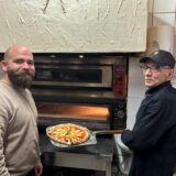 Der neue Inhaber Claudiu Craciun der Pizzeria Pronto Salvatore steht  gemeinsam mit dem ehemaligen Inhaber Salvatore Grasso (rechts) vor dem Pizzaofen. Salvatore Grasso hat gerade die Pizza aus dem Ofen geholt.