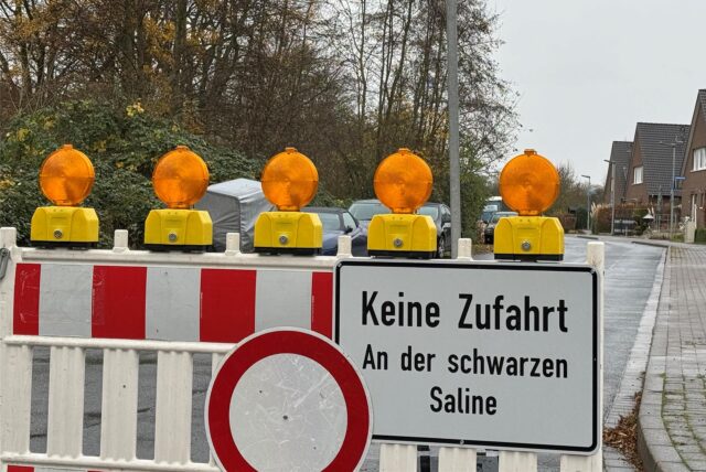 An der Vaersthausener Straße in Unna-Königsborn steht eine Absperrung mit dem Hinweis, dass die Zufahrt „An der Schwarzen Saline“ gesperrt ist. Darüber hängt ein Pfeil, der eine Umleitung nach links zeigt, an der gesperrten Brücke am Kuhlenbrink vorbei.