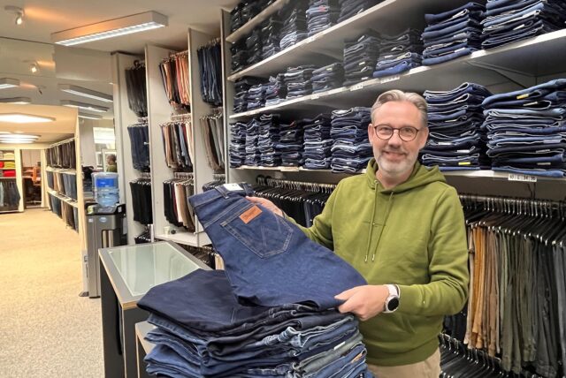 Thomas Weber, Inhaber des Modegeschäfts Hosen-Spezialist, zeigen Hosen vor einem langen Regal voller Ware