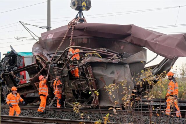 Mitarbeiter der DB bereiten die Bergung eines zerstörten Wagens durch einem Kran von den Gleisen vor.