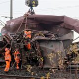 Mitarbeiter der DB bereiten die Bergung eines zerstörten Wagens durch einem Kran von den Gleisen vor.