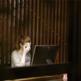 Eien Frau sitzt am Computer und hält sich eine Hand vors Gesicht.