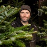 Landwirt Nils Henter aus Bergkamen steht inmitten von mehreren Weihnachtsbäumen.