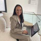 Die Dortmunder Immobilienmaklerin Asma Boufeljat sitzt auf einem Sofa und ht einen Laptop auf dem Schoß.
