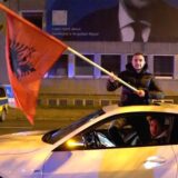 Zwei Männer fahren zum albanischen Nationalfeiertag mit ihrem Auto auf dem Wall in Dortmund und schwenken eine Albanien-Fahne.