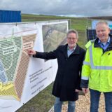Norbert Enters (Vorsitzender Gesellschafterversammlung der Solarpark GmbH) und Matthias Stephan (Geschäftsführer Solarpark Fröndenberg GmbH) stehen gemeinsam auf der Fläche der stillgelegten Deponie in Fröndenberg neben einem Bauplan für den Solarpark.