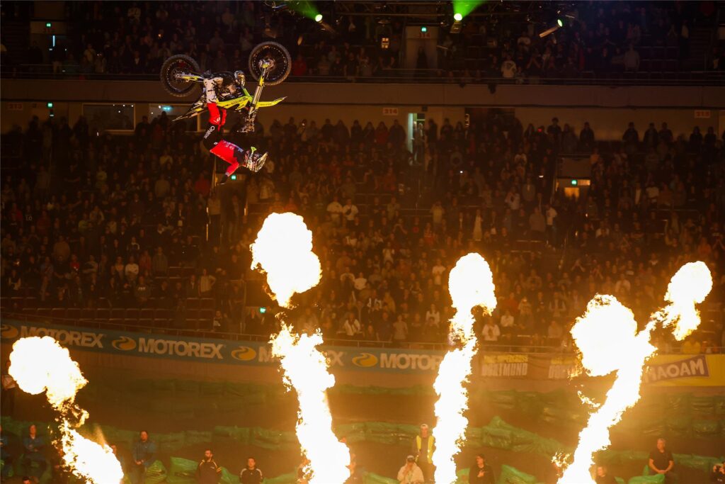 Ein Motocross Rad in der Luft über Flammensäulen in den Westfalenhallen Dortmund. Ein Motocross Rad in der Luft über Flammensäulen in den Westfalenhallen Dortmund.