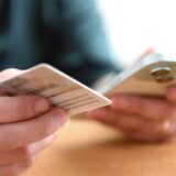 Eine Frau hält ihren Personalausweis und ihr Handy in der Hand.