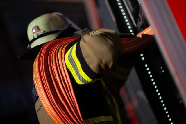 Ein Feuerwehrmann wickelt einen Schlauch ab