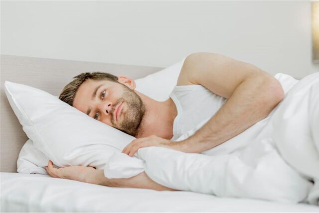 Ein Mann liegt im Bett und kann nicht einschlafen.