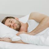 Ein Mann liegt im Bett und kann nicht einschlafen.