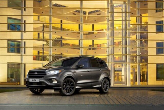 Ein Ford Kuga steht vor einem Glasgebäude.