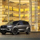 Ein Ford Kuga steht vor einem Glasgebäude.