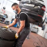 Ein Automechaniker stapelt in der Werkstatt Autoreifen.