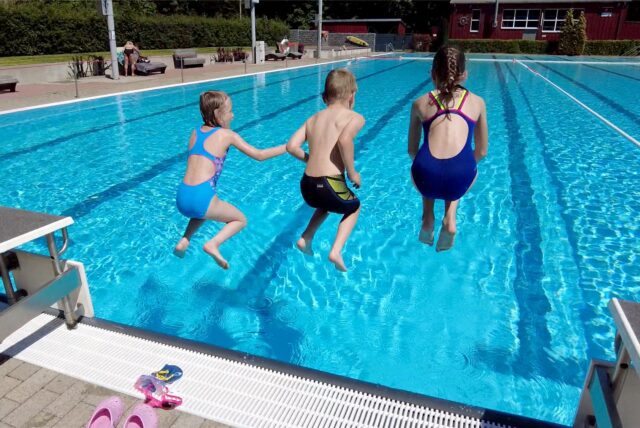 Kinder springen im Freibad Brambauer ins Becken.