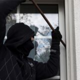Mit einer Brechstange versucht ein vermummter Einbrecher, eine Terrassentür aufzuhebeln (gestellte Szene).
