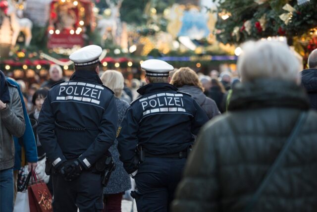 Polizeibeamte gehen über einen Weihnachtsmarkt. (Symbolbild)