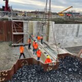 Bauarbeiter setzen am Adensee in Bergkamen ein Verschlussbauwerk ein.