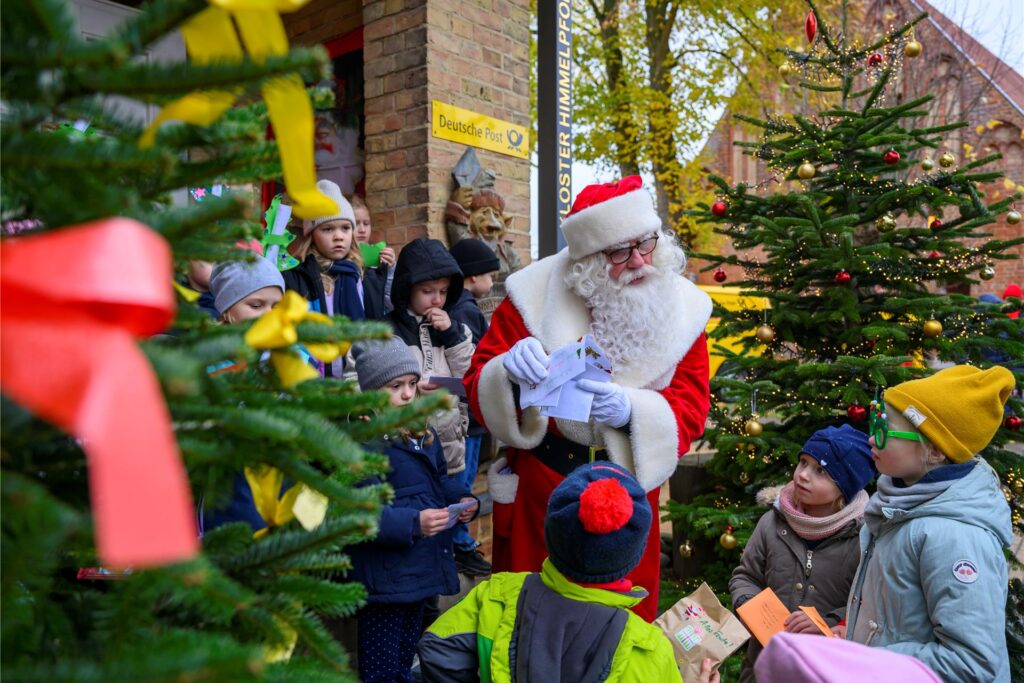 Weihnachtsmann steht mit Kindern vor dem Weihnachtspostamt. Weihnachtsmann steht mit Kindern vor dem Weihnachtspostamt.