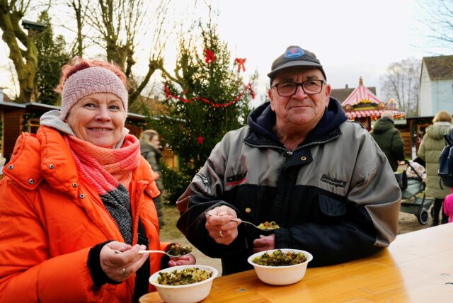 Zwei Besucher essen auf dem Weihnachtsmarkt der EWG in Schwerte-Ost.