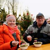 Zwei Besucher essen auf dem Weihnachtsmarkt der EWG in Schwerte-Ost.