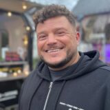 Ein Bild von Deniz Mert, direkt vor seinem „Toast House“ in Werne am Markt. Er lächelt in die Kamera.