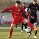 Noel Barucha (im roten Trikot) klärt den Ball vor dem Gegner.
