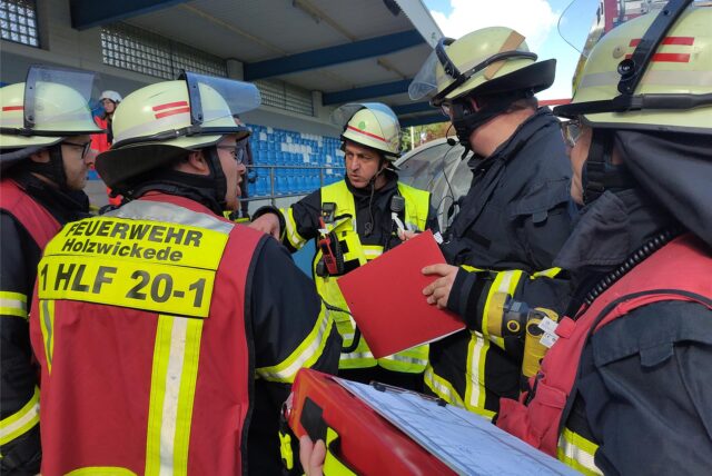 Holzwickeder Feuerwehrleute besprechen die Lage während einer großen Übung mit dem DRK in einem örtlichen Fußballstadion.
