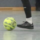 Ein Fußballer läuft mit dem Ball am Fuß, durch die Halle.
