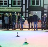 Mehrere Persinen stehen auf dem Eis und betreiben Eisstockschießen