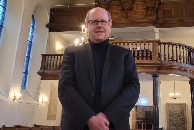 Der 51-jährige Gunther Antensteiner steht in einer Kirche und lächelt in die Kamera.