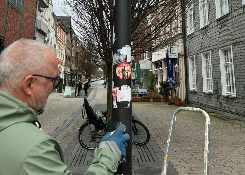 Ein Mann besprüht einen Laternenpfahl. Ein Mann besprüht einen Laternenpfahl.