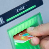 Ein Mann steckt eine EC-Karte in den Schlitz eines Geldautomaten