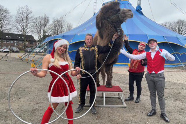 Artisten stehen mit einem Kamel vor dem Zelt des Dortmunder Weihnachtscircus.