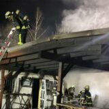 Mehrere Feuerwehrleute sind unter, auf und neben einem qualmenden Vordach.